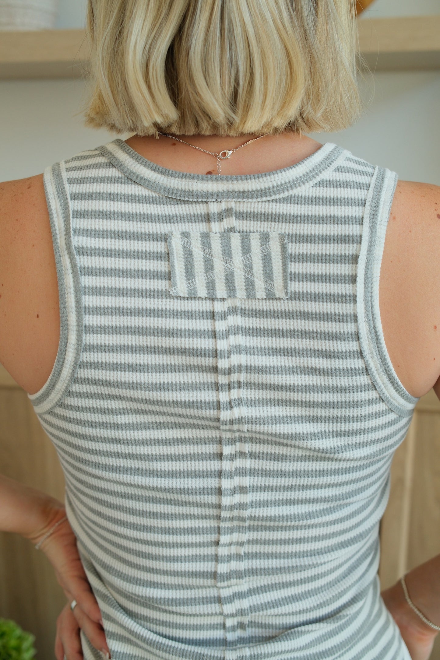 Person wearing a sleeveless striped shirt with a neutral background