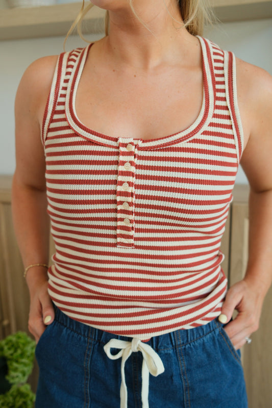 Person wearing a red and white striped tank top with blue pants.